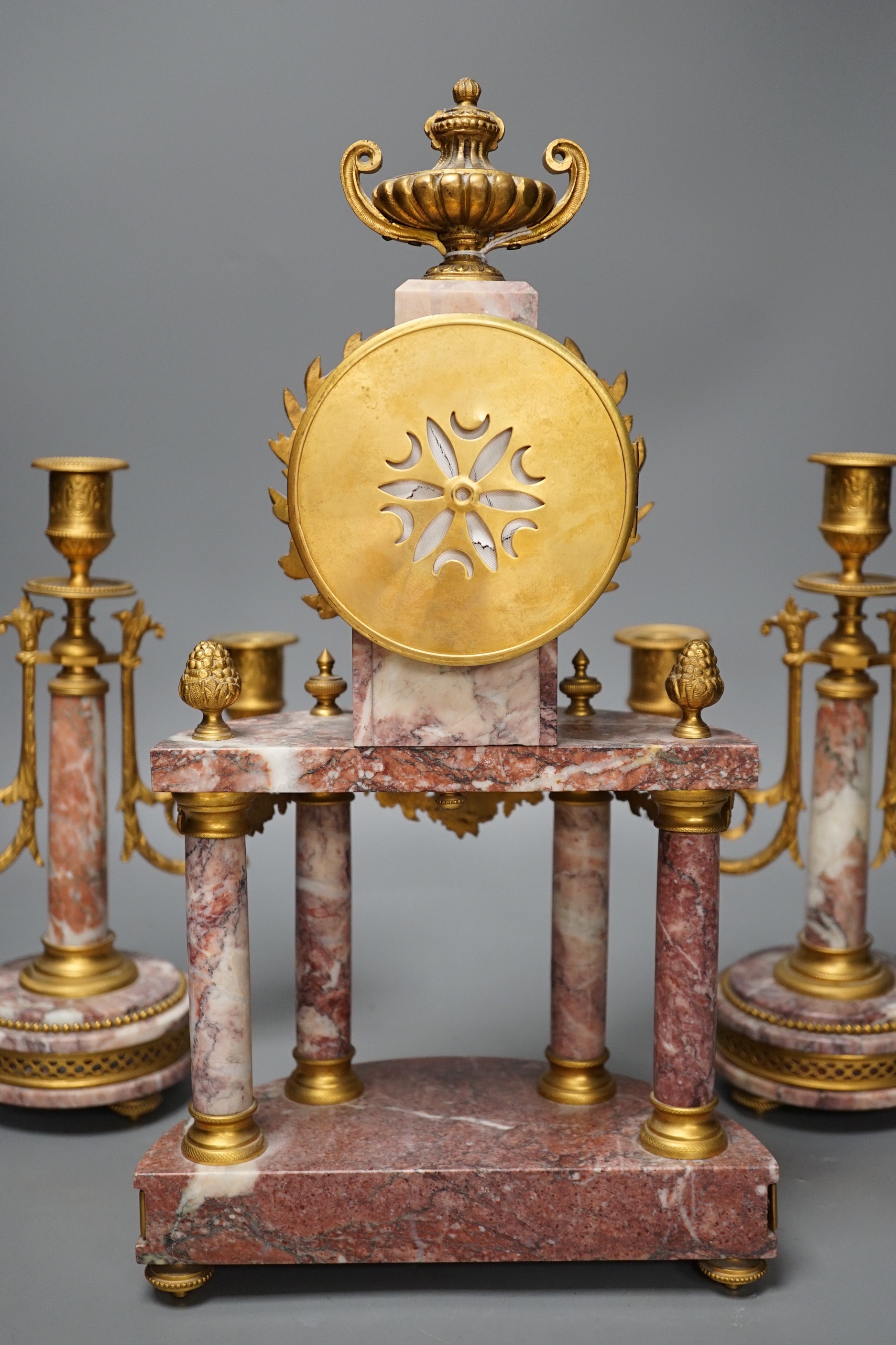 A French ormulu and rouge marble clock garniture, c.1900, with decorative enamel dial, 40cms high.